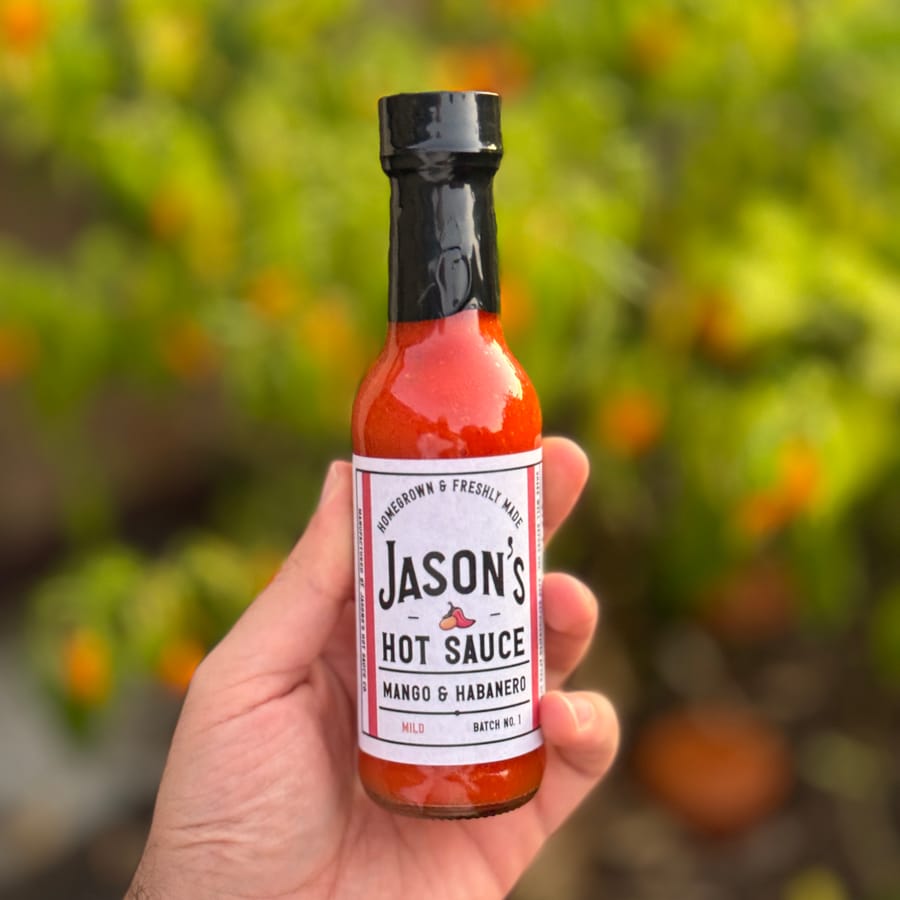 Jason holding the very first bottle, Batch No. 1, in front of the chilli garden
