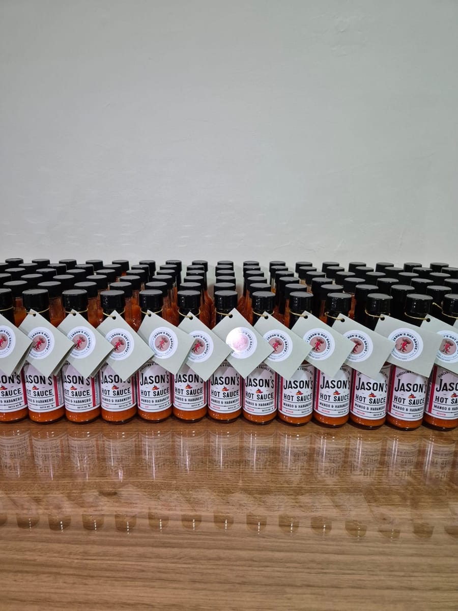 Rows of early Jason's Hot Sauce bottles with hand-tied tags